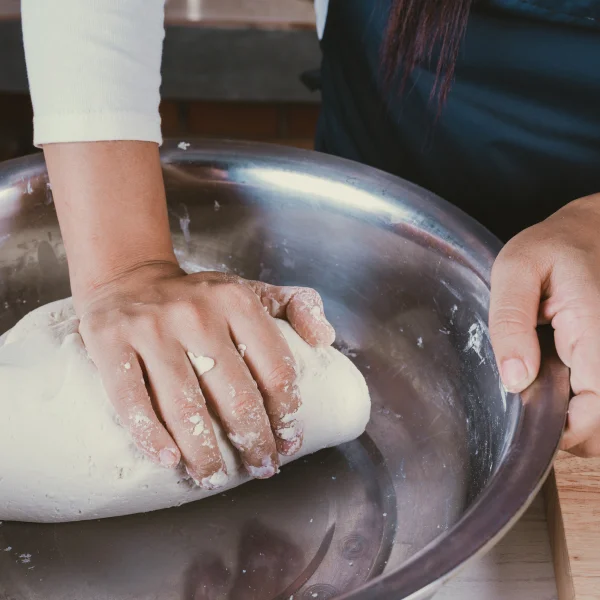 Le guide complet des équipements de boulangerie commerciaux 2 Une personne pétrissant de la pâte dans un bol, entourée d'équipements de boulangerie commerciaux.